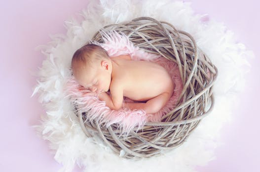 Example of Easter themed baby photography Glasgow with a baby laying on a feathery blanket inside an artificial nest